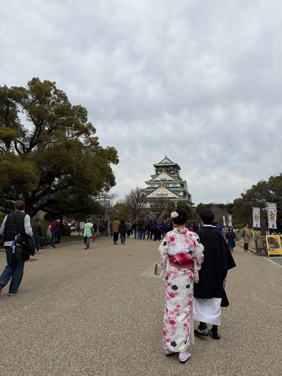 People in kimonos walking towards Osaka Castle, seen from behind